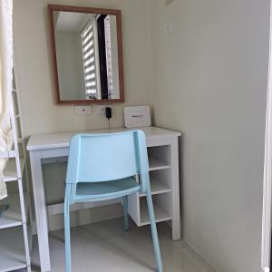 - un bureau avec une chaise bleue et un miroir dans l'établissement Brenthill Condo Suite, à Baguio