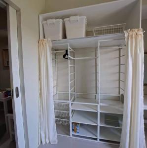 un placard avec des étagères blanches et un rideau dans l'établissement Brenthill Condo Suite, à Baguio