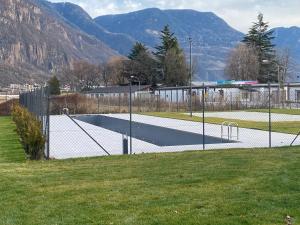 una pista de tenis en un campo con montañas al fondo en New Great Apartment Bolzano with 25m pool en Bolzano