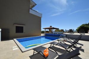 a swimming pool with chairs next to a house at Apartments Zrinka in Omišalj