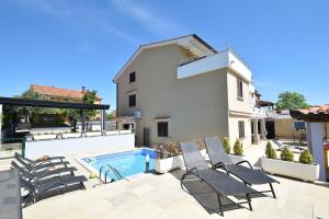 a villa with a swimming pool and patio furniture at Apartments Zrinka in Omišalj