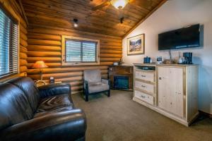 ein Wohnzimmer mit einem Sofa und einem TV in einer Hütte in der Unterkunft Flying Saddle Resort and Steak House in Alpine