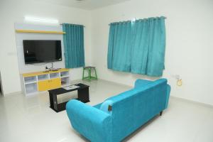 a living room with a blue couch and a tv at The best villa stay- family friendly in Coimbatore