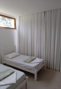 a bedroom with two beds and a window with curtains at Casa em Praia do Forte - Bahia in Praia do Forte