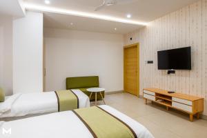 a hotel room with two beds and a flat screen tv at THE M HOTEL in Raipur