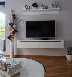 uma sala de estar com uma televisão e uma mesa em Apartman MAJA em Vrnjačka Banja