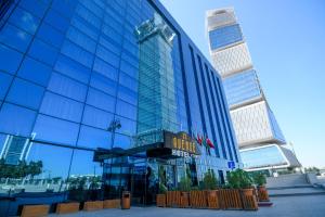 un grand bâtiment en verre avec un panneau sur celui-ci dans l'établissement Avenue Hotel Baku by Smart, à Baku