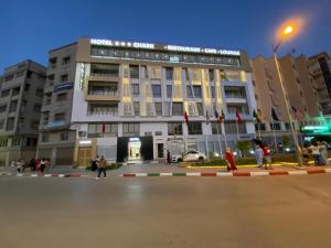 un grand bâtiment avec des personnes debout devant lui dans l'établissement Hôtel Chark, à Guercif