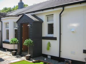 a house with a black door and two potted plants at Ivy Cottage in Dunoon