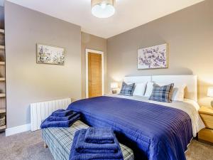 a bedroom with a large bed with blue comforter at Ivy Cottage in Dunoon