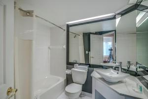 a bathroom with a toilet and a sink and a mirror at Hotel Quality Suites in Sainte-Anne-de-Beaupré