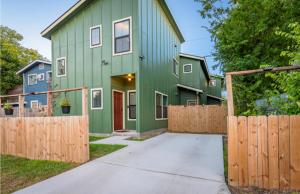 a green house with a wooden fence in front of it at Eastlawn Place cozy 2 bdrm townhome near downtown San Antonio in San Antonio