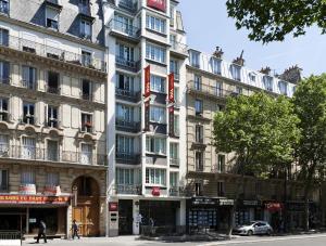 un grand bâtiment blanc dans une rue de la ville dans l'établissement ibis Paris Ornano Montmartre Nord 18ème, à Paris