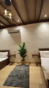 a room with two beds and a potted plant at كوخ البيلسان in Al Shafa