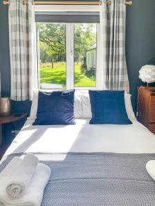 a large bed with blue pillows and a window at Old Kyle Farm in Kyleakin