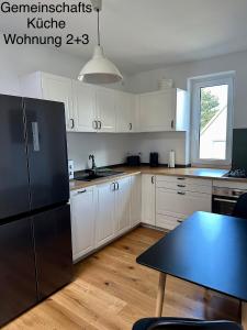 eine Küche mit weißen Schränken und einem schwarzen Kühlschrank in der Unterkunft Ferienwohnungen Tenner in Jüterbog