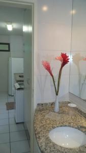 a bathroom with a sink and a vase with flowers on it at Apartamento Temporada Maceió in Maceió