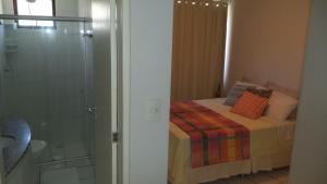 a bedroom with a bed and a glass shower at Apartamento Temporada Maceió in Maceió