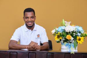 a man sitting at a table with a bouquet of flowers at The Highbridge Guest Lodge in Accra