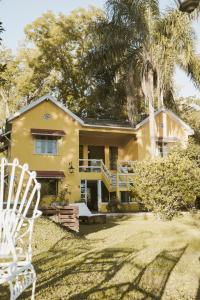 ein gelbes Haus mit einer Palme und zwei weißen Stühlen in der Unterkunft Casona del Rio in Tigre