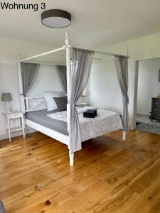 ein Schlafzimmer mit einem Himmelbett und einem Holzboden in der Unterkunft Ferienwohnungen Tenner in Jüterbog