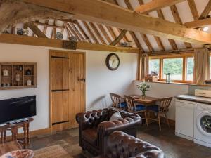 een woonkamer met lederen meubels en een eettafel bij Heron Barn in Hollingbourne