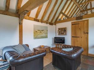 a living room with two leather couches and a tv at Heron Barn in Hollingbourne