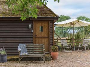 een houten hut met een bank en een parasol bij Heron Barn in Hollingbourne