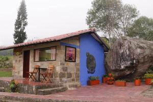 a small blue cottage with a large rock at Confortable cabaña para que disfrute con su pareja in Santandercito