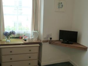 a bedroom with a dresser with a television on a desk at Grey Mullet Guesthouse in St Ives