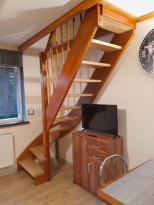 a living room with a wooden staircase with a flat screen tv at Apartamenty rodzinne U Zośki 1 in Łukęcin
