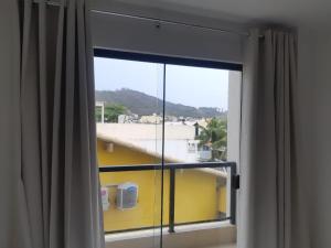 une fenêtre avec vue sur un bâtiment jaune dans l'établissement Pousada Areia Branca, à Arraial do Cabo
