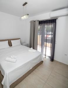 - une chambre avec un lit blanc et une grande fenêtre dans l'établissement Mary's luxury apartment Elaia., à Elia Laconias