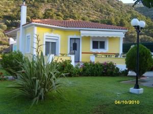 a small yellow house in a yard with a grass at Elisabeth Villas in Kerveli