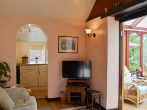 a living room with a flat screen tv on a stand at The Old Stable _ E4126 in Southrey