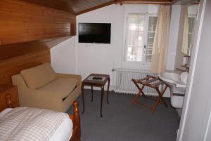 um quarto com uma cama, uma cadeira e uma televisão em Baeren Hotel, The Bear Inn em Wilderswil