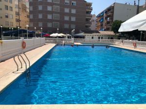 ein großer Pool mit blauem Wasser in einer Stadt in der Unterkunft Green Palmeral Los Locos Torrevieja in Torrevieja