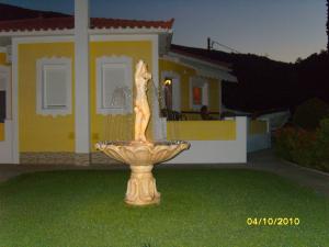 a fountain in the grass in front of a house at Elisabeth Villas in Kerveli