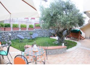 patio ze stołami, krzesłami i drzewem w obiekcie A 2 Passi Dagli Dei w mieście Agerola