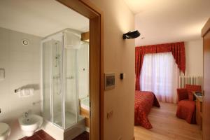 a bathroom with a shower and a sink and a bed at Garni Lago Nembia in San Lorenzo in Banale