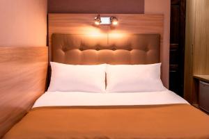 a bed with a wooden headboard and lights on it at Tourist Chernivtsi in Chernivtsi