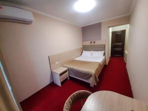 ein kleines Schlafzimmer mit einem Bett und einem roten Teppich in der Unterkunft Tourist Chernivtsi in Czernowitz