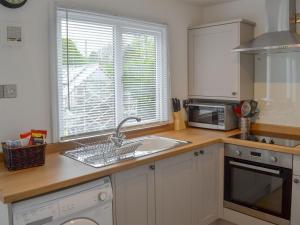 a kitchen with a sink and a microwave and a window at Josnor Chalet in Benllech