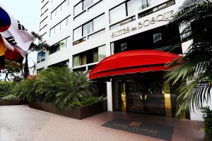 un edificio con un toldo rojo delante de él en Suites del Bosque Hotel en Lima