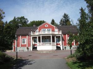 een groot rood huis met een witte veranda bij Rönninge Gård in Rönninge