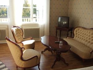 a living room with a couch and chairs and a tv at Rönninge Gård in Rönninge