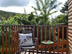 a chair sitting on a deck with a table at Curlew Cottage in Creetown