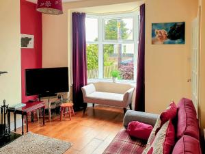a living room with a couch and a tv and a window at Curlew Cottage in Creetown