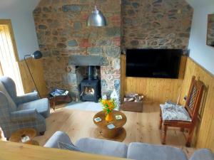 a living room with a fireplace and a stone wall at Braeside Cottage - Adorable 2 Bedroom Eco-Friendly Character Cottage in Pitlochry