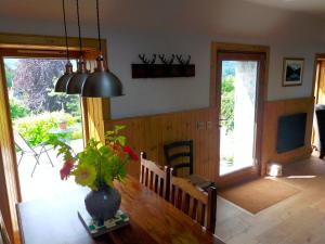 ein Esszimmer mit einem Tisch und einer Vase aus Blumen in der Unterkunft Braeside Cottage - Adorable 2 Bedroom Eco-Friendly Character Cottage in Pitlochry